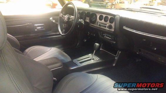Car interior with gray seats, dashboard, steering wheel, and center console with automatic shifter