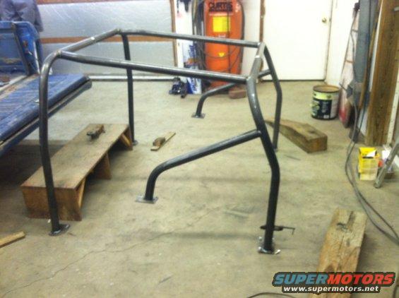 Roll cage frame in a garage with a blue seat visible