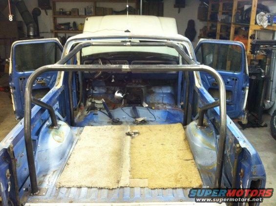 Interior of a blue pickup truck undergoing modification with a custom roll cage installed