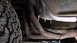 1979 Ford Bronco - Close-up view of a vehicle's exhaust manifold and tire, with a watermark for Supermotors.net visible.