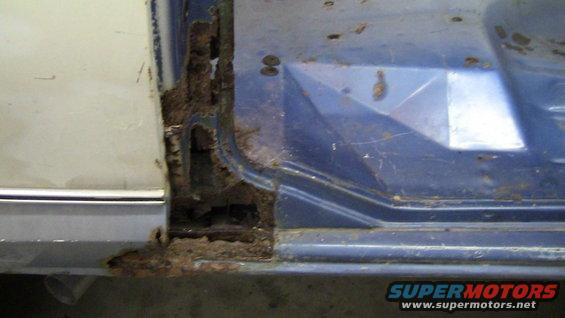 Rusted door sill on a blue and white vehicle