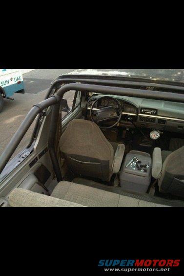 Interior of a 1995 Ford Bronco showing dashboard, seats, and roll cage