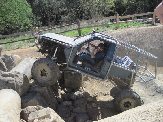 Custom off-road buggy with roll cage navigating a rocky obstacle