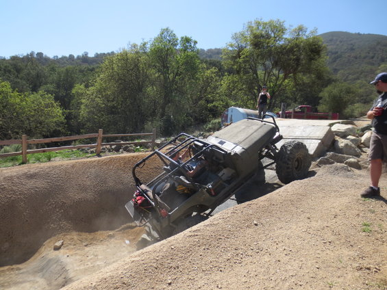 Off-road vehicle navigating a steep dirt incline with a roll cage