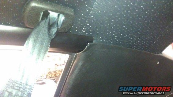 Black car interior with a seatbelt and a speckled headliner