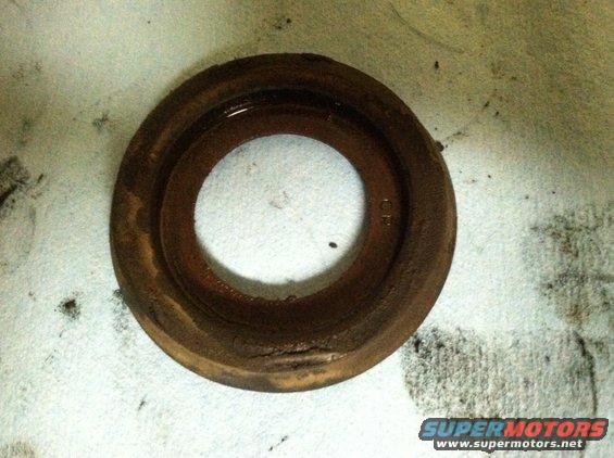 Rusty metal ring with a circular opening, resting on a textured surface. Some dark smudges are visible