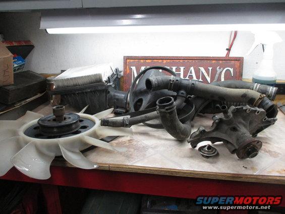 Radiator hoses, fan, water pump, and thermostat on a workbench