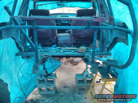 SUV interior with roll cage, seats, and center console visible, covered in blue tarp