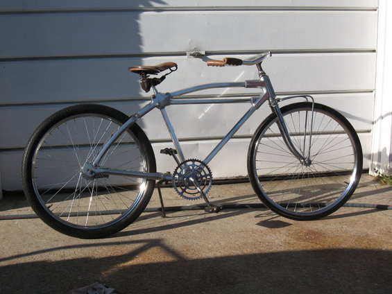 Silver cruiser bicycle with leather seat and handlebars parked on concrete