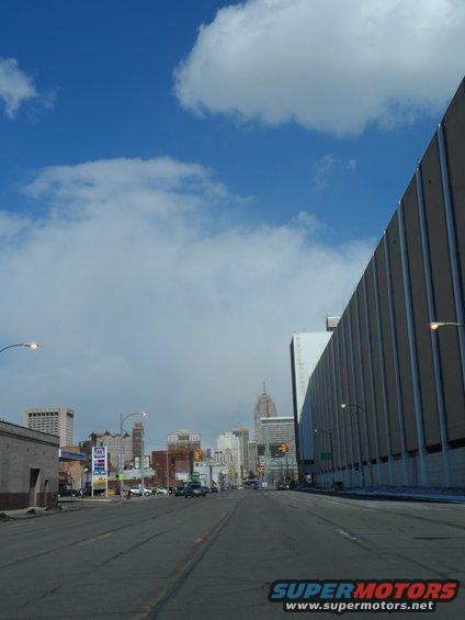 Street view of a city with tall buildings and a large modern structure on the right