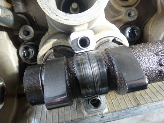 Worn camshaft with visible scoring and oil residue