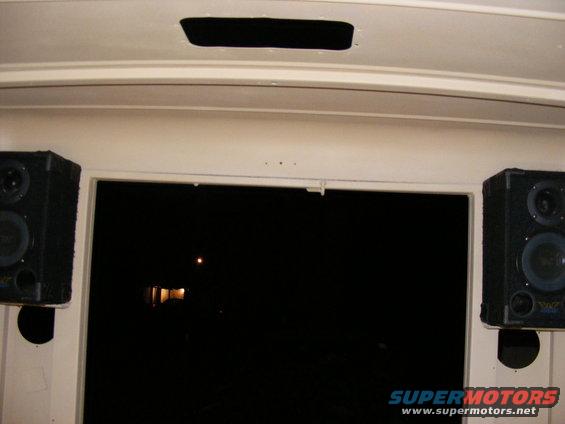 Interior view showing two speakers mounted near a dark window with a faint light reflection