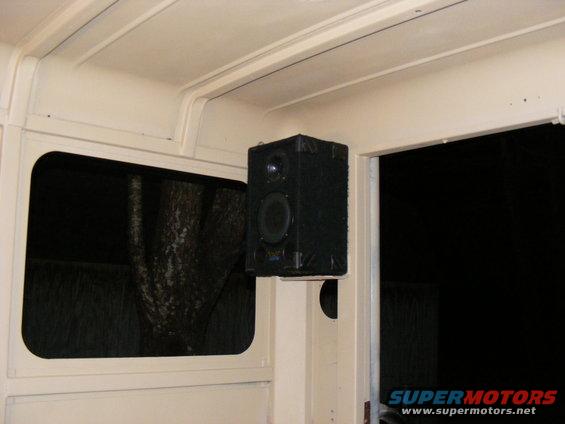 Interior view of a vehicle showing a black speaker mounted on a pillar next to a window
