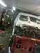 1995 Ford F-150 - A truck is in a garage, undergoing repairs with its engine exposed and front body panels removed.