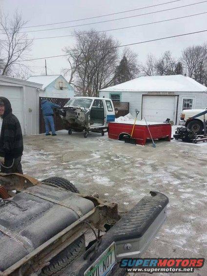 Truck chassis with fuel tank, red truck bed, and white cab with blue stripe on wheels