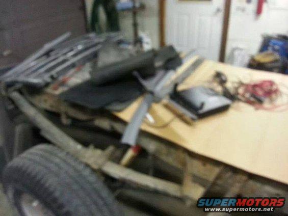 Truck chassis with leaf springs and tire, disassembled parts on a wooden surface