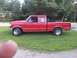 1995 Ford F-150 - A red 1995 Ford F-150 pickup truck is parked on a grassy area with trees in the background.