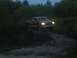 1995 Ford F-150 - A red pickup truck navigates a dirt path surrounded by foliage as twilight deepens.