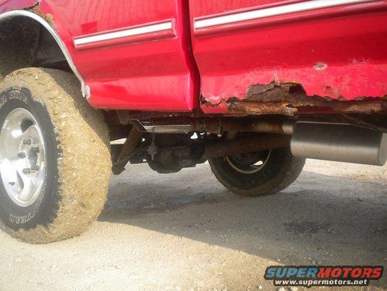 Side view of rusty red 1995 Ford F-150 lower body with mud-caked tire