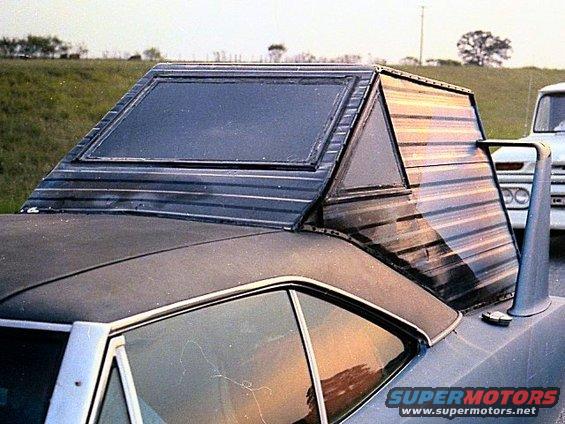 Custom camper shell with large window on car's rear, another vehicle visible