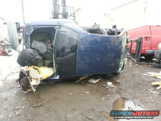 Blue 2004 Mercury Grand Marquis on its side in a junkyard