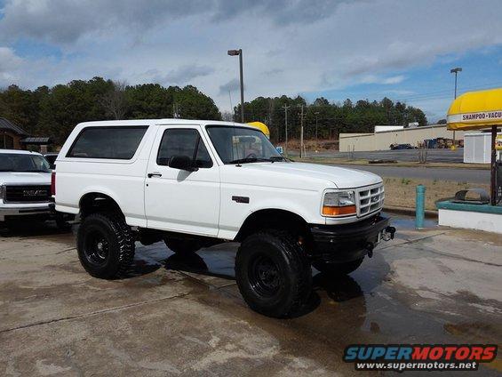 White 1995 Ford Bronco parked outside, another white SUV to the left