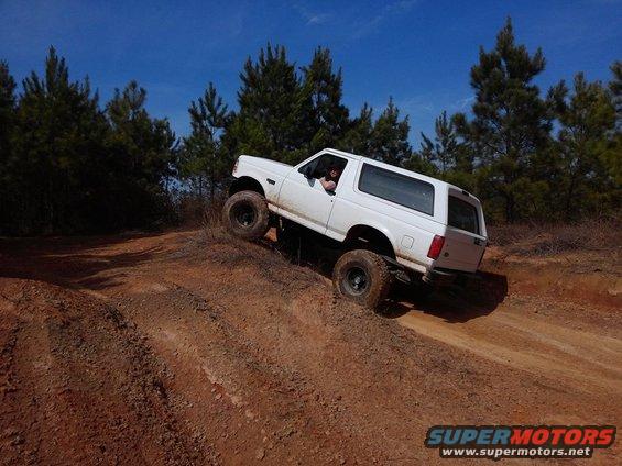 White 1995 Ford Bronco climbing a dirt hill off-road