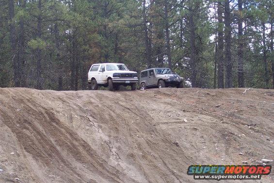White 1992 Ford Bronco parked on a dirt incline next to a silver Jeep Wrangler