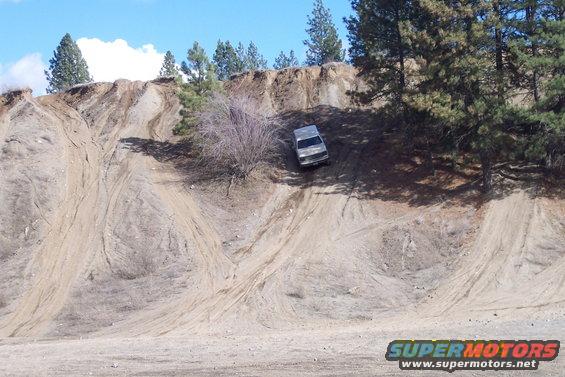 Silver SUV on a steep dirt hill with tire tracks