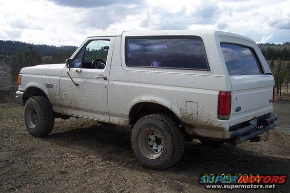 White 1990 Ford Bronco parked on a dirt hill, side view