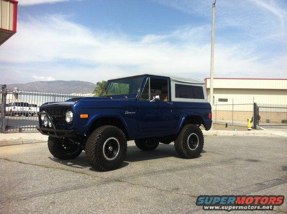 Blue 1986 Ford Bronco with a soft top and aftermarket bumper