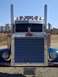 2003 Peterbilt 379 - Frontal view of a blue 2003 Peterbilt 379 truck with a prominent chrome grille and dual exhaust stacks.