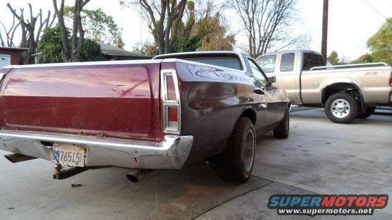 Rear view of a maroon 1972 Ford Ranchero parked next to a silver pickup truck