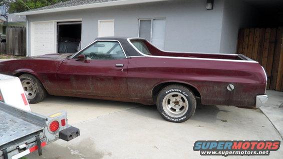 Maroon Ford Ranchero parked in driveway next to garage. Trailer in foreground