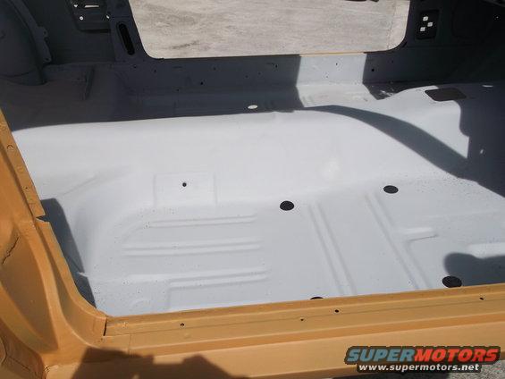 Car interior floor, painted white, with yellow door sill. Shadow visible