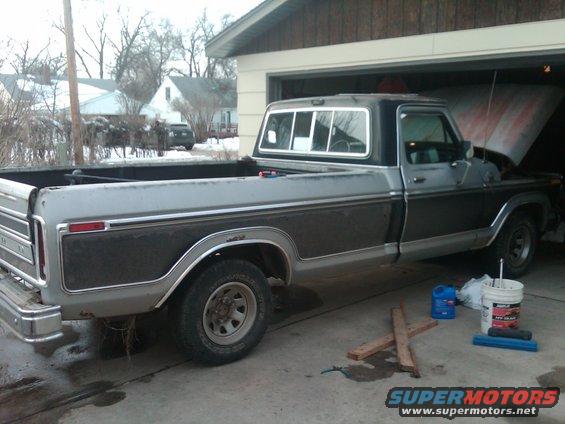 Gray and dark gray 1977 Ford F-150 pickup truck parked in a driveway with the hood open
