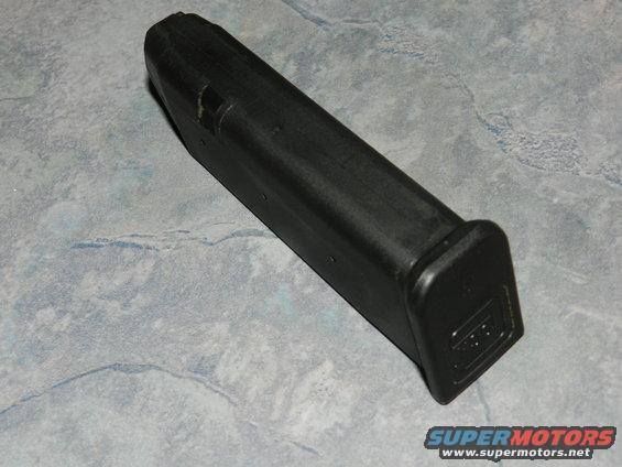 Black gun magazine with "GLOCK" logo on the base, resting on a gray, marbled surface