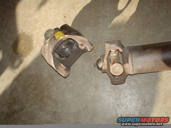 Close-up of a broken driveshaft universal joint on a concrete surface