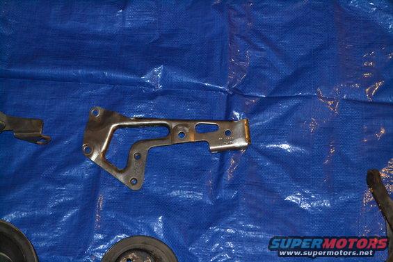 Metal bracket with multiple holes and a pulley on a blue tarp