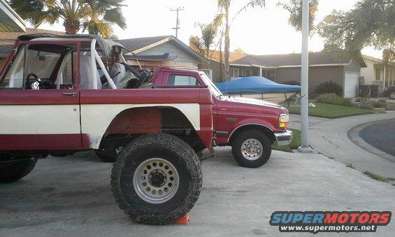 Big red and white off-road vehicle next to a red pickup truck