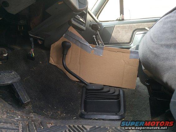 Interior shot of a truck's center console area with a cardboard box taped over it, obscuring the shifter