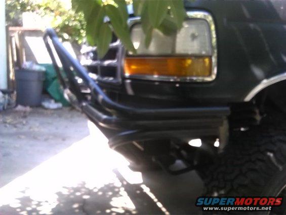 Front bumper and headlight of a dark SUV with a brush guard