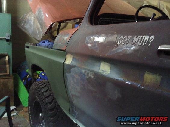 Side of a truck body with primer and bondo, has 'GOT MUD?' text on door