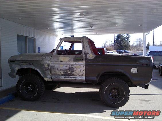 Old Ford Bronco, primer and rust showing, lifted with off-road tires