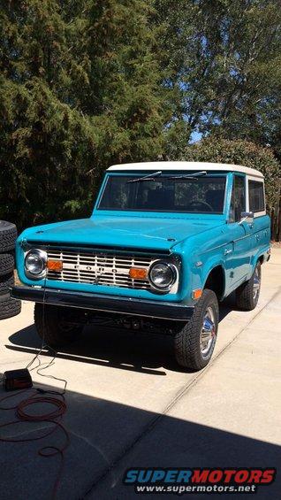 Blue 1968 Ford Bronco with white roof and chrome grille parked on a driveway