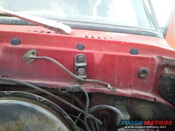 Close-up of red vehicle firewall with wiring and a windshield wiper arm