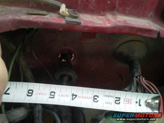 Red metal surface with wiring and a tape measure showing 7 inches