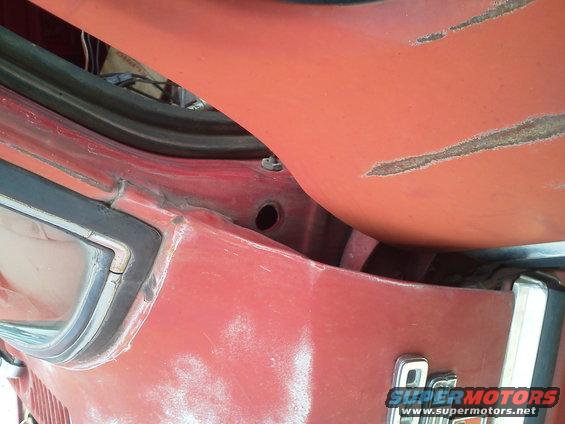 Close-up of red interior car panel with visible wiring and rubber seal