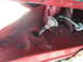 1979 Ford F-150 - A rubber grommet and wiring are visible in a section of red painted metal, likely part of a vehicle's body.