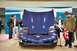 1992 Mercury Grand Marquis - A group of people gather around a blue Chevrolet Corvette C5 with its hood open at an indoor event.